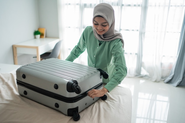 Beautiful Muslim women trying to close her full suitcase