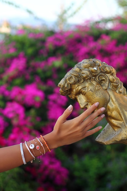 a beautiful nail polished female hand touches the garden statue Fashion concept