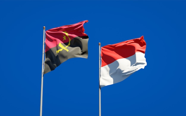 Foto belle bandiere di stato nazionali dell'indonesia e dell'angola insieme sul cielo blu