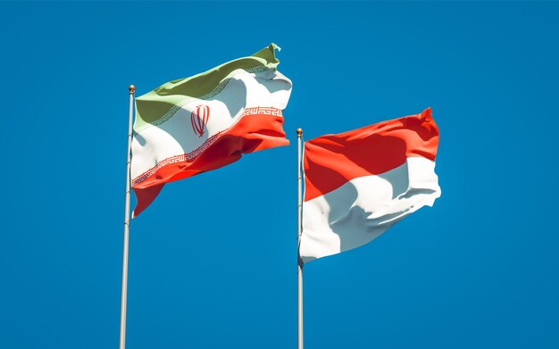 Красивые национальные государственные флаги Ирана и Индонезии вместе на голубом небе