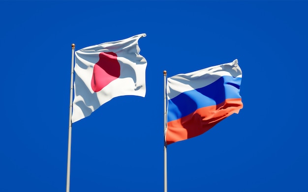 Beautiful national state flags of Japan and Russia together on blue sky. 3D artwork