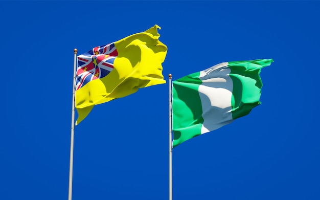 Beautiful national state flags of Niue and Nigeria together on blue sky