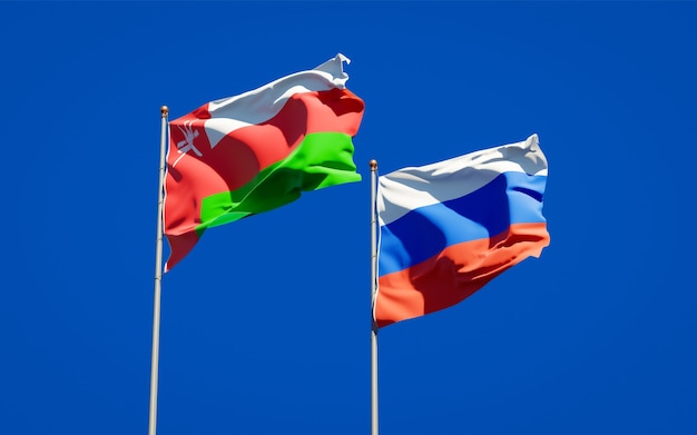 Beautiful national state flags of Oman and Russia together on blue sky. 3D artwork