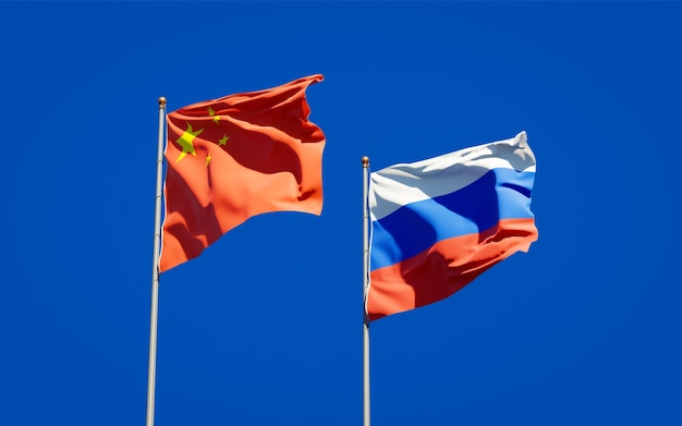 Beautiful national state flags of Russia and China together on blue sky. 3D artwork