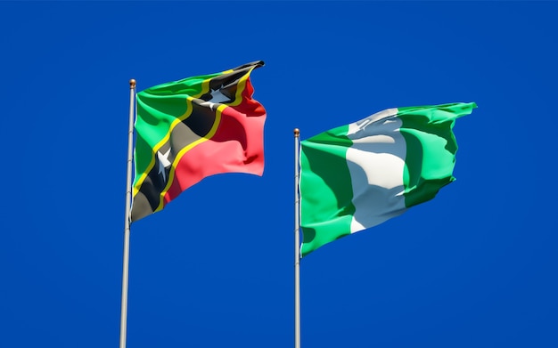 Belle bandiere dello stato nazionale di saint kitts e nevis e nigeria insieme sul cielo blu