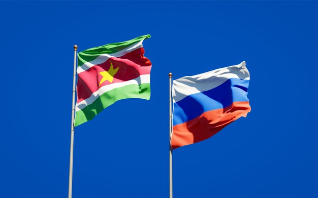 Belle bandiere di stato nazionali del suriname e della russia insieme sul cielo blu. grafica 3d