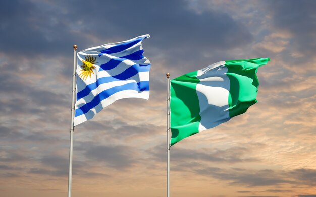 Belle bandiere di stato nazionali dell'uruguay e della nigeria insieme sul cielo blu