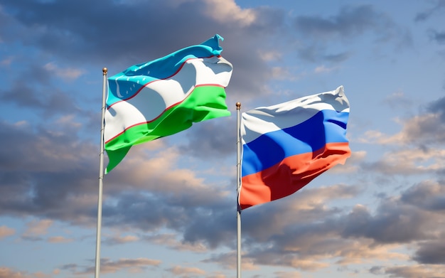 Beautiful national state flags of Uzbekistan and Russia together on blue sky. 3D artwork