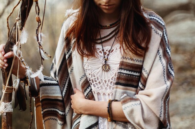 Photo beautiful native indian american woman holding pikestaff with dreamcatcher on background of woods