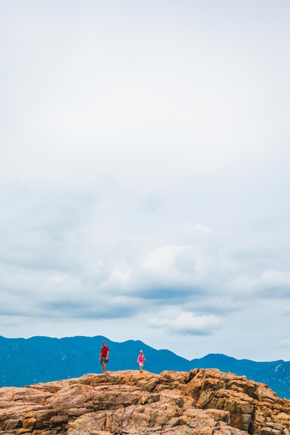 Beautiful natural composition vivid orange brown yellow stone rock shabby cliff cracks man boy child silhouette cumulus cloud sky mountain background Vacation after pandemic beauty nature power