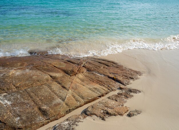 Beautiful natural rocks on the sandy beach and turquoise sea waves.