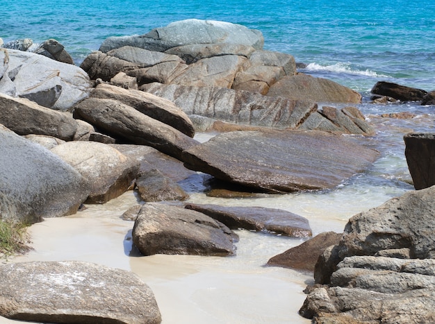 Belle rocce naturali sulla spiaggia sabbiosa e onde del mare turchese.