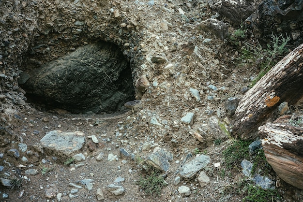 山の穴に大きな黒い石と美しい自然の背景。暗い岩の中空のクローズアップで大きな黒い岩のあるミニマリストの山の風景。山の大気の自然のミニマリズム。