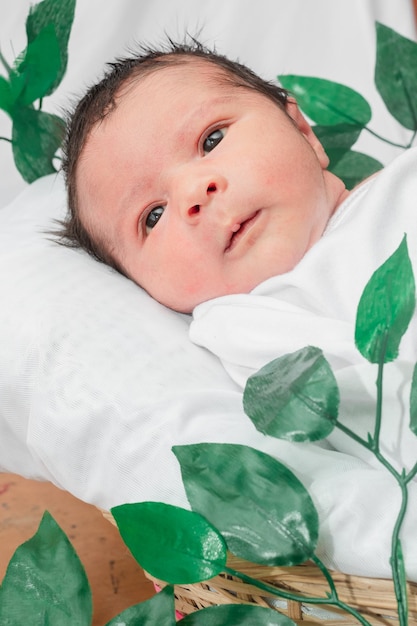 Beautiful newborn baby 4 days old lying with his eyes open disheveled in bamboo fiber basket