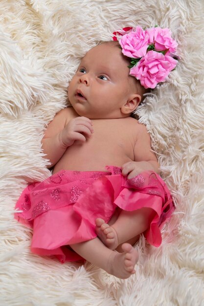 Beautiful newborn baby girl in pink clothes on a fur bed