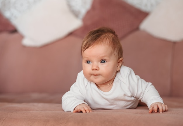 美しい新生児の女の子はベッドの上で彼女のおなかの上に横たわっています