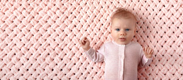 Beautiful newborn girl on a pink knitted plaid,