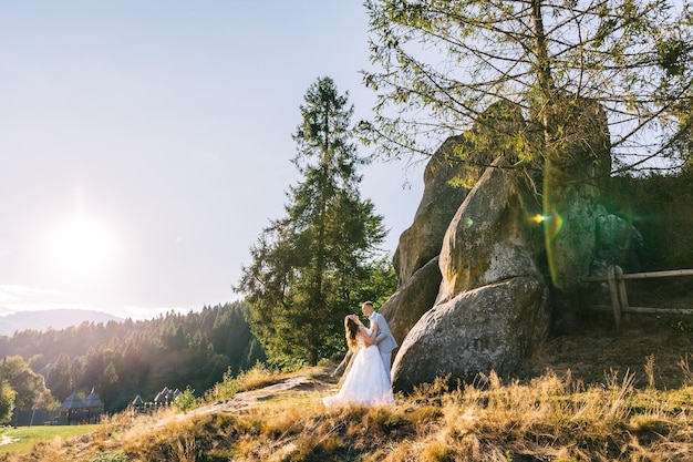 Beautiful newlyweds against the backdrop of a mountain forest landscape love of travel and extreme bride and groom on a wedding trip wedding in the mountains