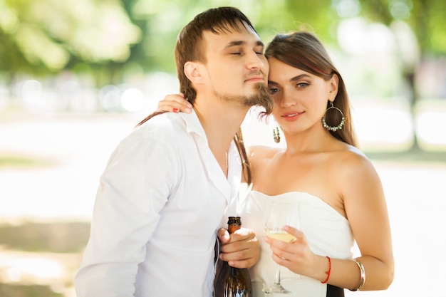 Beautiful newlyweds drinking champagne outdoors.