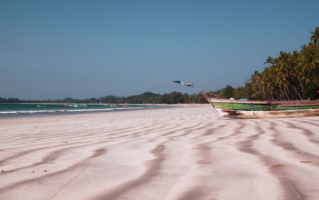 Beautiful Ngapali beach with striped sand and blue sea water, colorful boats on background, Myanmar