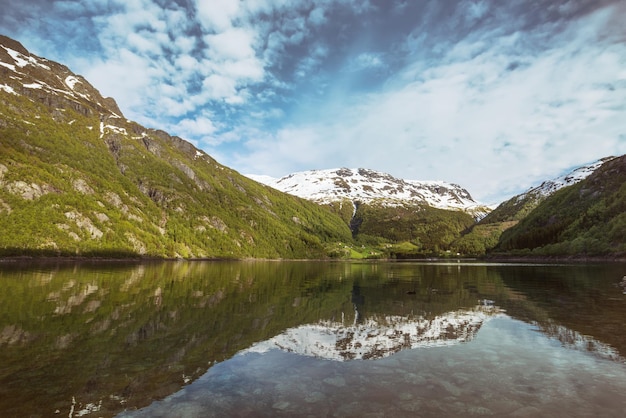Красивый норвежский пейзаж горы в снегу и отражение в водеxA