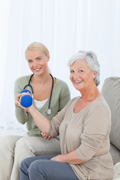 Beautiful nurse helping her patient to do exercises