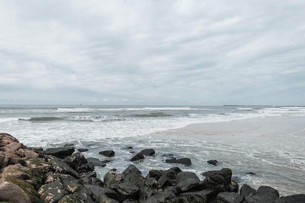 Beautiful ocean beach with rocks on an overcast day with clouds