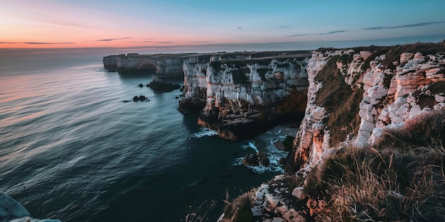 A beautiful ocean view with a rocky shoreline The sky is a mix of orange and blue hues creating a se