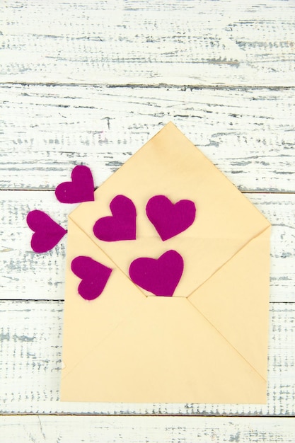 Beautiful old envelope with decorative hearts on wooden background