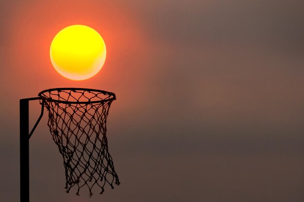 Photo beautiful orange rounded sun to gets into netball net