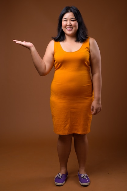 beautiful overweight Asian woman wearing orange sleeveless dress 