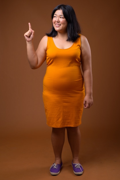 오렌지 민소매 드레스를 입고 아름다운 과체중 아시아 여자