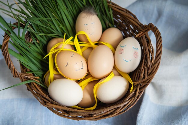 Beautiful painted Easter eggs with a cute face which lie in a wooden basket along with green grass Easter postcard