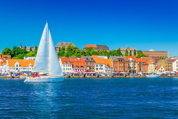 Photo beautiful panorama of a european port city. a yacht is sailing against the skyline of the city of flensburg, germany