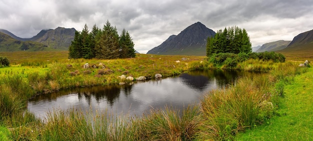Beautiful panoramic landscape of high mountains trees and lakes in the glencoe valley scotland
