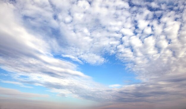 Beautiful panoramic sky landscape with white flying clouds extending over the skyline line