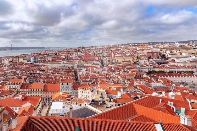 Beautiful panoramic view of Lisbon city with red tiled roofs under a cloudy sky.