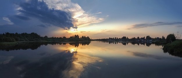 湖に沈む夕日と水の反射の美しいパノラマビュー。