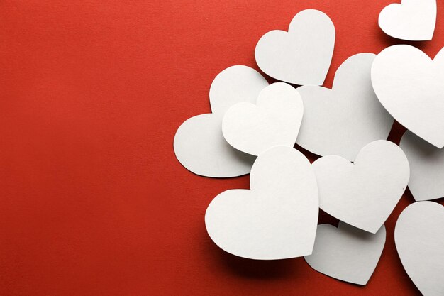 Beautiful paper hearts on red paper background