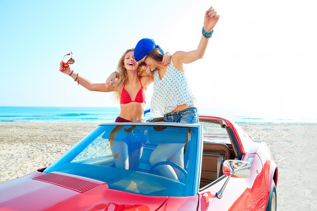 Belle ragazze festa ballando in una macchina sulla spiaggia