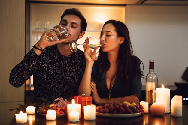 Beautiful passionate couple having a romantic candlelight dinner at home, drinking wine, toasting