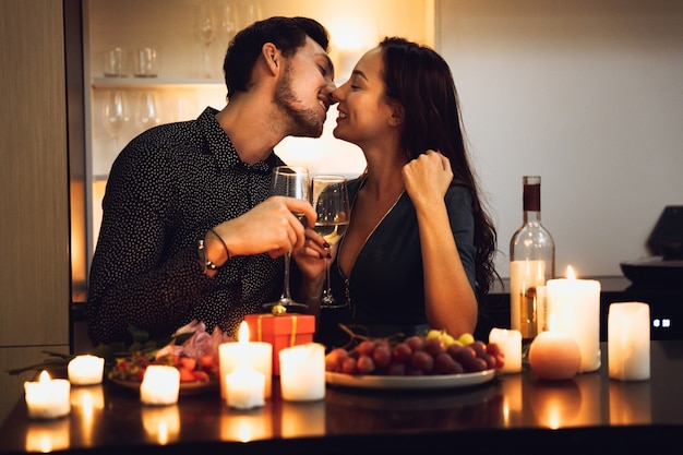 Beautiful passionate couple having a romantic candlelight dinner at home, drinking wine, toasting