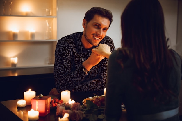 Photo beautiful passionate couple having a romantic candlelight dinner at home, man kissing hand