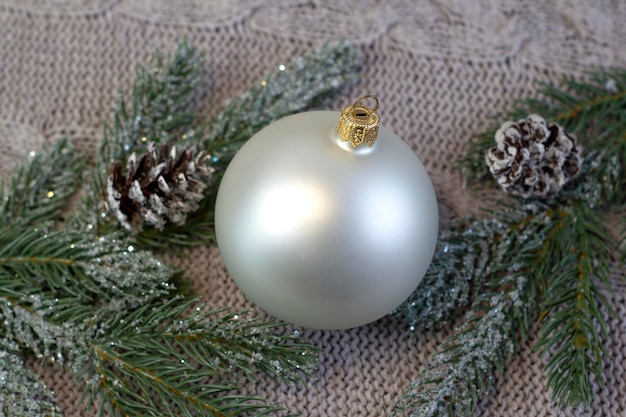 Beautiful pearl Christmas ball with patterns in on a cozy light knitted background close up