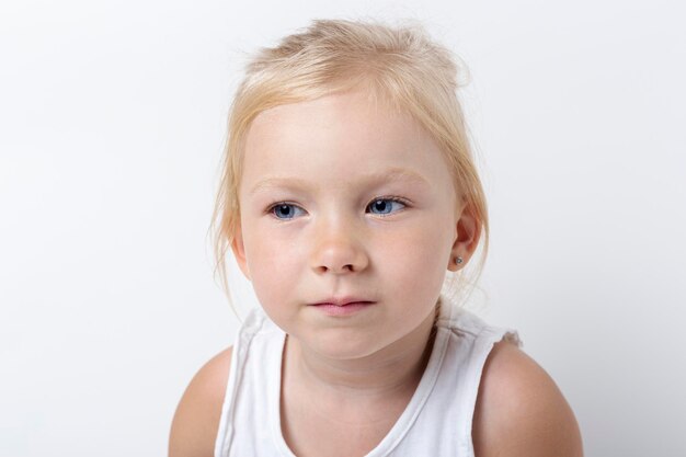 Beautiful pensive blonde girl on a light background in the studio.