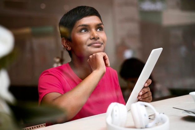 Bella donna indiana pensierosa che usa lo shopping digitale online, scegliendo qualcosa