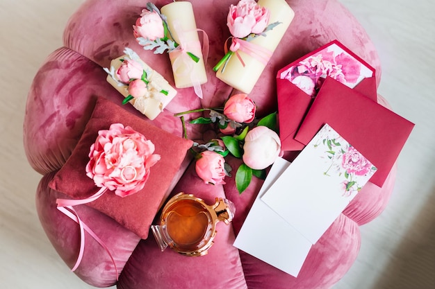 beautiful peonies invitations and perfumes lie on the pink soft armchair