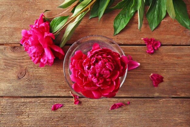 Beautiful peony in glass on wooden background