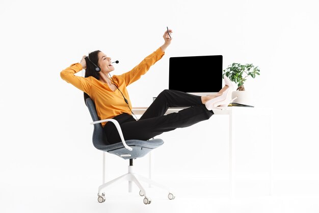 beautiful phone operator woman wearing microphone headset holding smartphone while sitting at her workplace in office