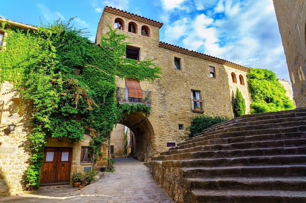 Madremanya Girona Spain의 거리와 높은 계단에 석조 아치가 있는 아름답고 그림 같은 광장